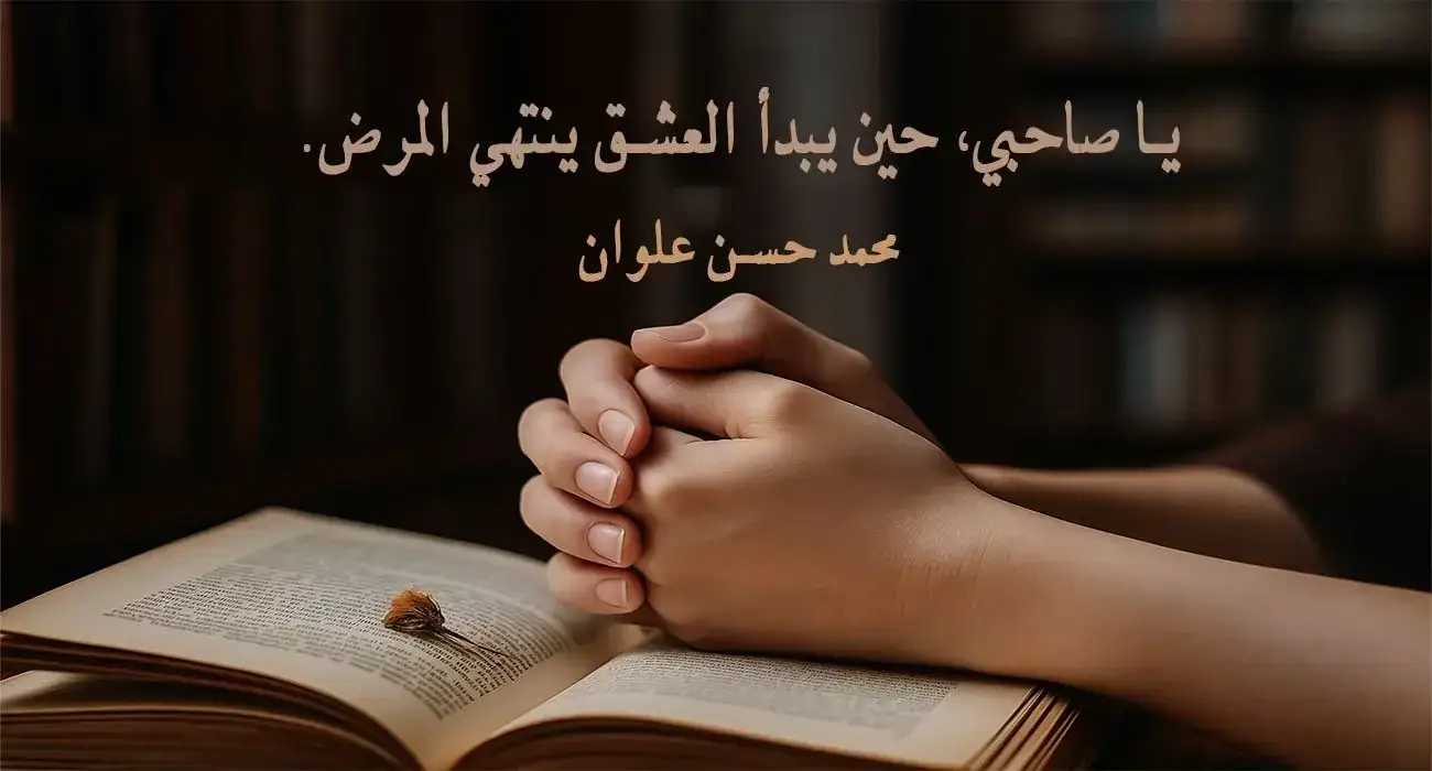يدان متشابكتان فوق كتاب مفتوح يعرض اقتباس عن الحب والعشق للكاتب محمد حسن علوان، ضمن مقالة عن اقتباسات عن الحب من الكتب والروايات.